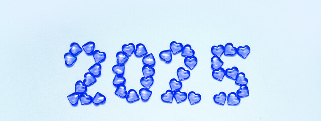 New Year 2025 inscription from glass hearts on a blue background. Pantone color 2025. Idea and creativity. Valentine's Day. Christmas with loved ones. Horizontally, banner. High quality photo