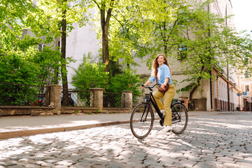 Happy woman tourist using bicycle in city street. Free time after work and study, lifestyle. Eco...