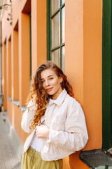 Fototapeta premium Optimistic woman with curly hair walking on the street city. Concept of lifestyle, fashion, travel.