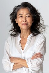 A woman stands with her arms crossed, wearing a white shirt