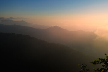 Landscape horizon line in the mountains, orange sunset and blue mountains.