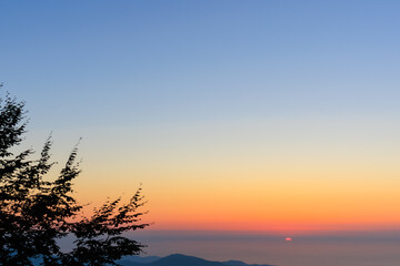 Landscape horizon line in the mountains, pink orange sunset and blue mountains.