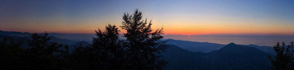 Landscape horizon line in the mountains, pink orange sunset and blue mountains.