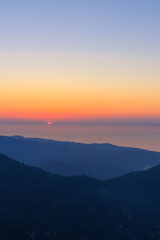 Landscape horizon line in the mountains, orange sunset and blue mountains.