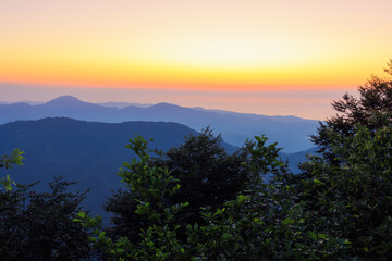 Landscape horizon line in the mountains, orange sunset and blue mountains.