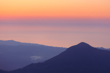 Fototapeta premium Landscape horizon line in the mountains, orange sunset and blue mountains.