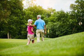 Mature, couple and walk back on golf field, outside and healthy fitness activity with golfers together with club. Relaxing, weekend break and care on sport course, nature exercise and people