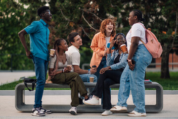 Cheerful diverse group of college students talking and smiling at campus
