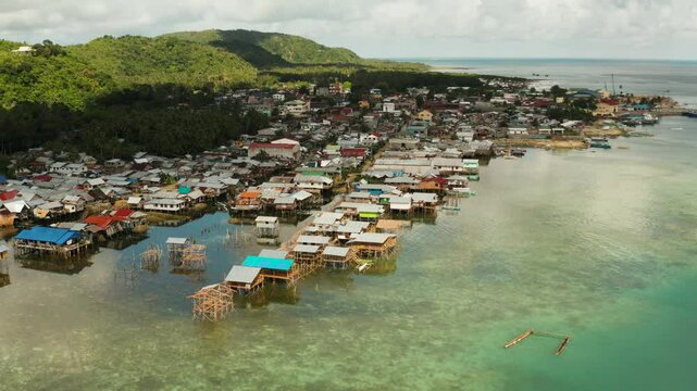 Old wooden house standing on the sea in the fishing village, aerial view. Dapa, Siargao, Philippines.