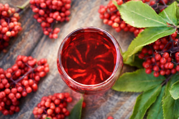 Herbal syrup made of red elderberry or Sambucus racemosa fruit in a glass on a table, top view