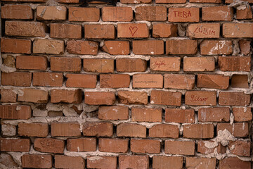 Obraz premium Old damaged broken shabby red brick wall of an old building. Brick texture with scratches and cracks. Grunge background with cracked grey blueish stucco. Close up. Copy space