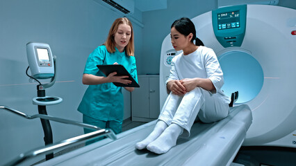 Doctor holding tablet and showing result of MRI. Patient lying at MRI capsule. MRI cabinet. Modern...