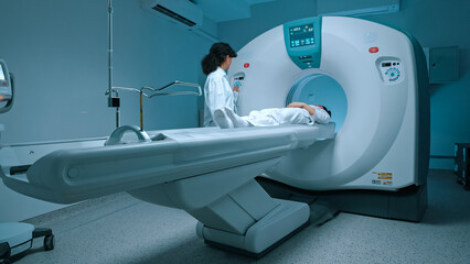Patient in white clothes undergoes magnetic resonance imaging scan, laying down on bed for CT or...