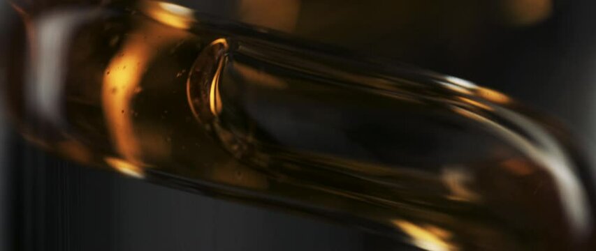 abstract extreme macro of liquid running through a glass spiral with small bubbles, amber color, warm, slow motion