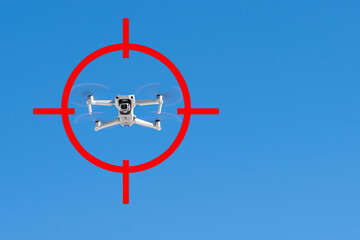 Gun sight pointing at drone flying against blue sky. Concept of flight ban and safety