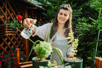 One young caucasian woman is taking care of her plants using plant mister and water can	