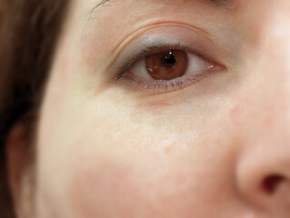 Closeup of brown eye iris and face of young Caucasian Spanish European white skin woman.
