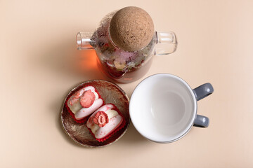 Glass teapot with flower tea with cups and macaroons top view