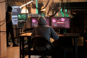 Cybercrime, internet thief hacking computer system, stealing data. Hacker sending virus, breaking into database server, coding spyware, programming malicious software, back view