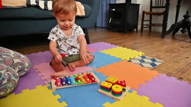 A toddler, baby bot 10-12 months old, is playing a colorful xylophone with a parent. The scene is warm and nurturing, depicting early childhood development and bonding.