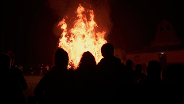 silhouettes of unrecognizable people observing a large bonfire during the night of san juan in the principality of asturias, Spain. Ancient pagan festival of Litha. 