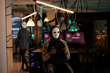 Cybercriminal in mask hacking computer password to steal information, breaking into online server....