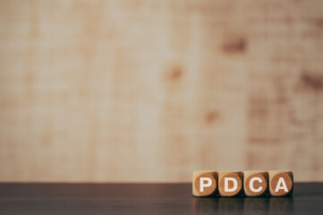 There is wood cube with the word PDCA. It is an abbreviation for Plan, Do, Check, Act as eye-catching image.