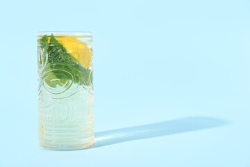 Glass of icy fresh mint tea and lemon on blue background