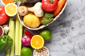 Wicker bowl with different fresh vegetables and cereals on blue background, closeup