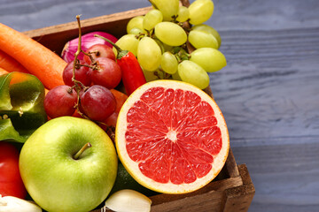 Box with different fresh fruits and vegetables on blue wooden background, closeup