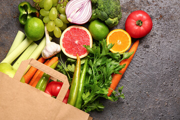 Paper bag with different fresh fruits and vegetables on dark background