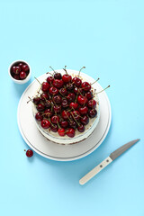 Plate with tasty cherry cake on blue background