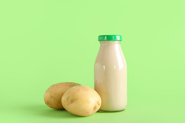 Bottle of tasty potato milk on green background