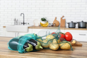 Eco bags with different ripe vegetables on counter in kitchen, closeup