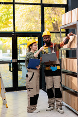 Stockroom employee looking at cardboard boxes during inventory, preparing packages for customers orders. Small business team working at delivery process analyzing checklist on laptop