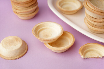 Bowl with homemade tartlets on lilac background