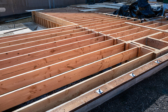 New home construction, subfloor built on foundation, sill plates installed with anchor bolts, floor joists in place, ready for plywood layer
