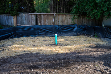 Sewar system newly installed in ground with blue PVC pipe sticking out and capped, straw covering...