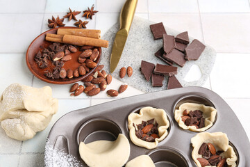 Composition with muffin tray and ingredients for bakery on light tile background, closeup