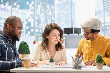 Real estate experts examining architectural blueprints with client, evaluating the financial potential of the property office space for investment. Business woman negotiating with realtors.