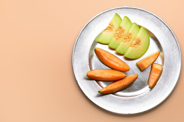 Plate with slices of tasty ripe melon on orange background