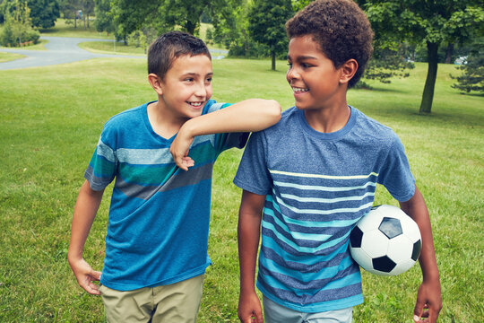 Children, boys and walking in field with soccer ball in park for happiness, development or bonding together. Friends, nature and diverse kids with smile for fun, morning or adventure on weekend