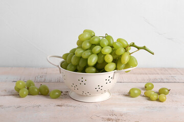 Juicy sweet grapes in a colander on  wooden background