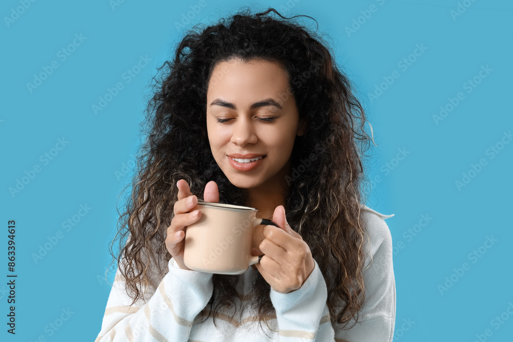 Sticker Beautiful young African-American woman with cup of hot mulled wine on blue background