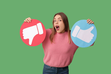 Beautiful young shocked woman with like and dislike icons on green background