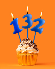 Blue candle number 132 - Birthday cupcake on orange background