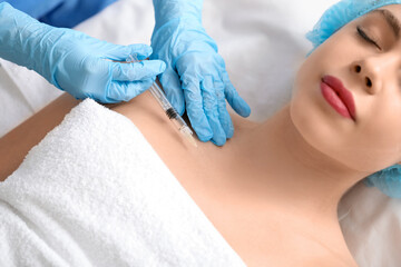 Naklejka premium Young woman receiving filler injection in beauty salon