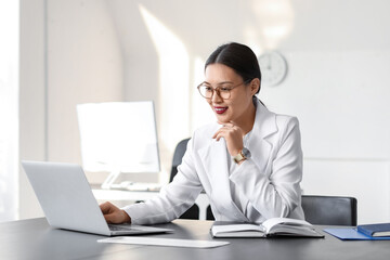 Fototapeta premium Young Asian businesswoman working with laptop at table in office