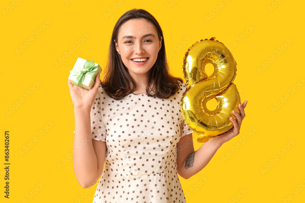 Canvas Prints Beautiful young woman with golden air balloon in shape of figure 8 and gift box on yellow background. International Women's Day