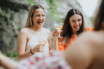 Joyful friends celebrating at a picnic, drinking champagne and laughing in the outdoors. They are enjoying each others company and the natural surroundings.